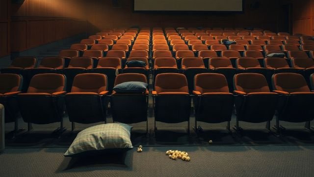 Rows of empty cinema seats with popcorn scattered on the floor